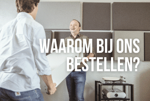 Een lachende man in een groen blouseje en een jongere man met een wit blouseje tillen een witte high-end luidspreker of speaker in een winkel. OP de achtergrond staat een versterker en in witte letters staat de blog titel "waarom bestellen bij ons"