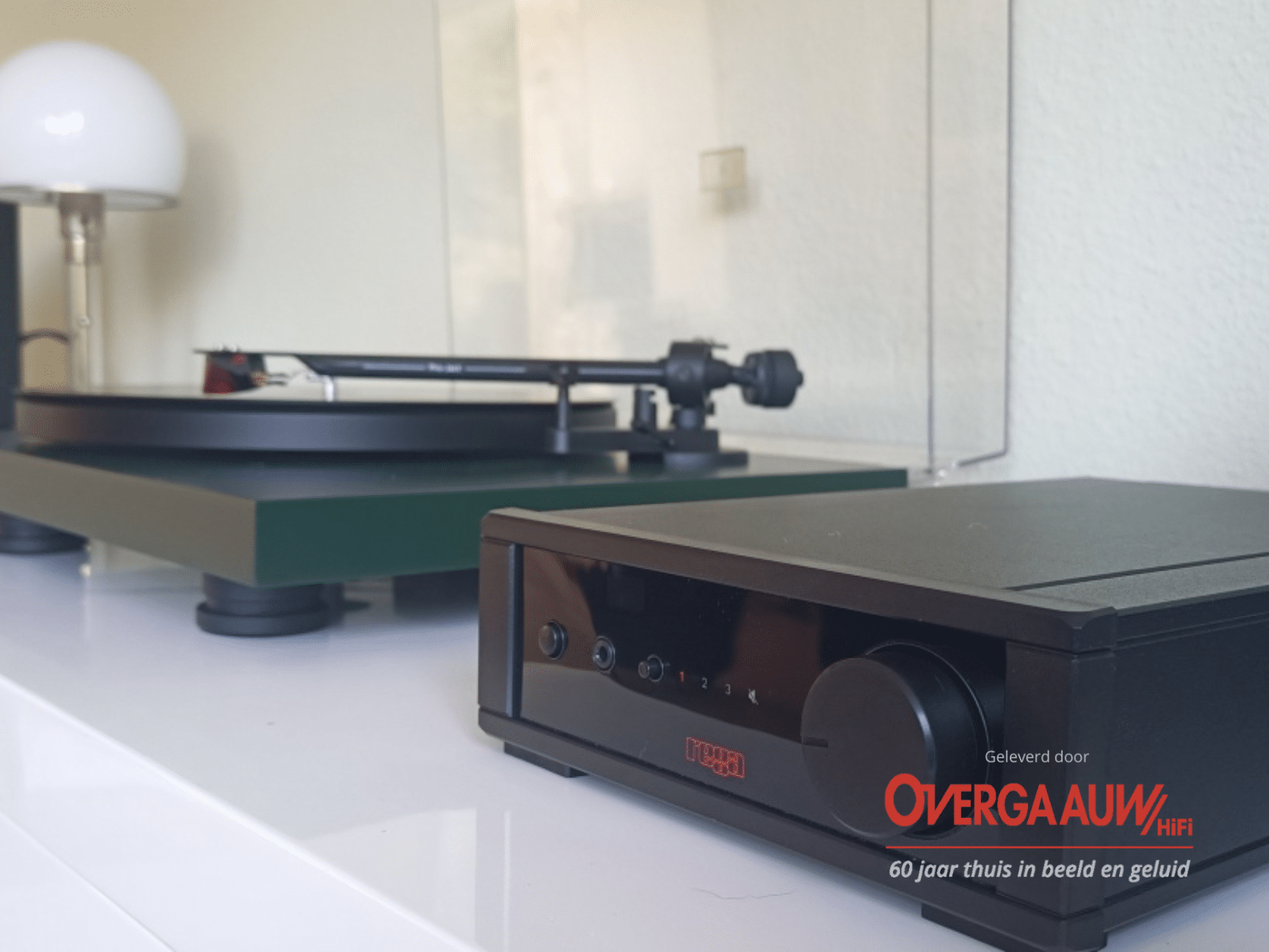 Een mosgroene Pro-ject platenspeler aangesloten op een Rega compact versterker met rood licht display