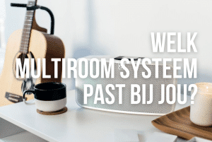 Witte BlueSound speaker van het Bluos systeem op een wit kastje met een gitaar er naast en een kopje koffie met een kaarsje met de blogtekst "welk multiroom systeem past bij jou" erop in het wit. Voor Overgaauw Leiden